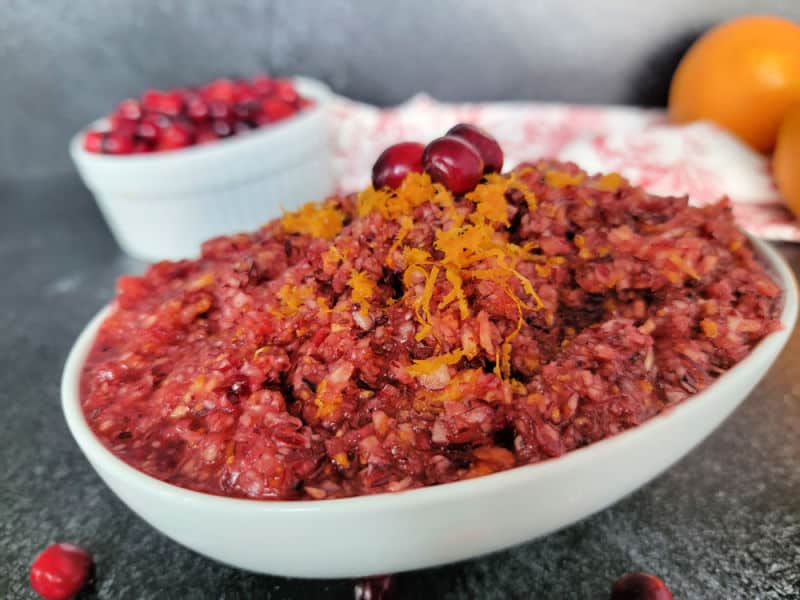 cranberry orange relish garnished with orange zest and cranberries in a white bowl