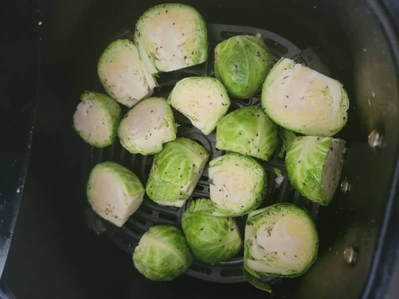 Brussel sprouts cut in half in an air fryer basket