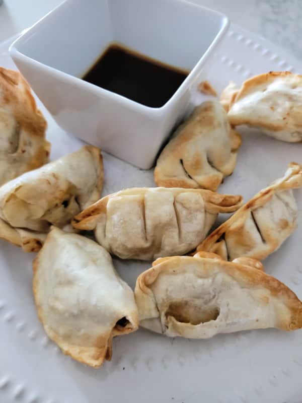 air fried dumplings on a white plate next to dipping sauce