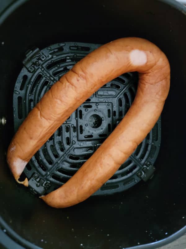 Kielbasa in an air fryer basket before air frying