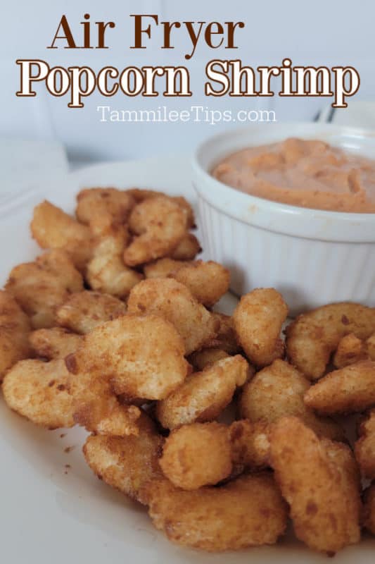 Air fryer popcorn shrimp over a plate of shrimp with a bowl of sauce