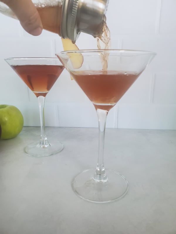 cocktail shaker pouring a Washington apple drink into a martini glass
