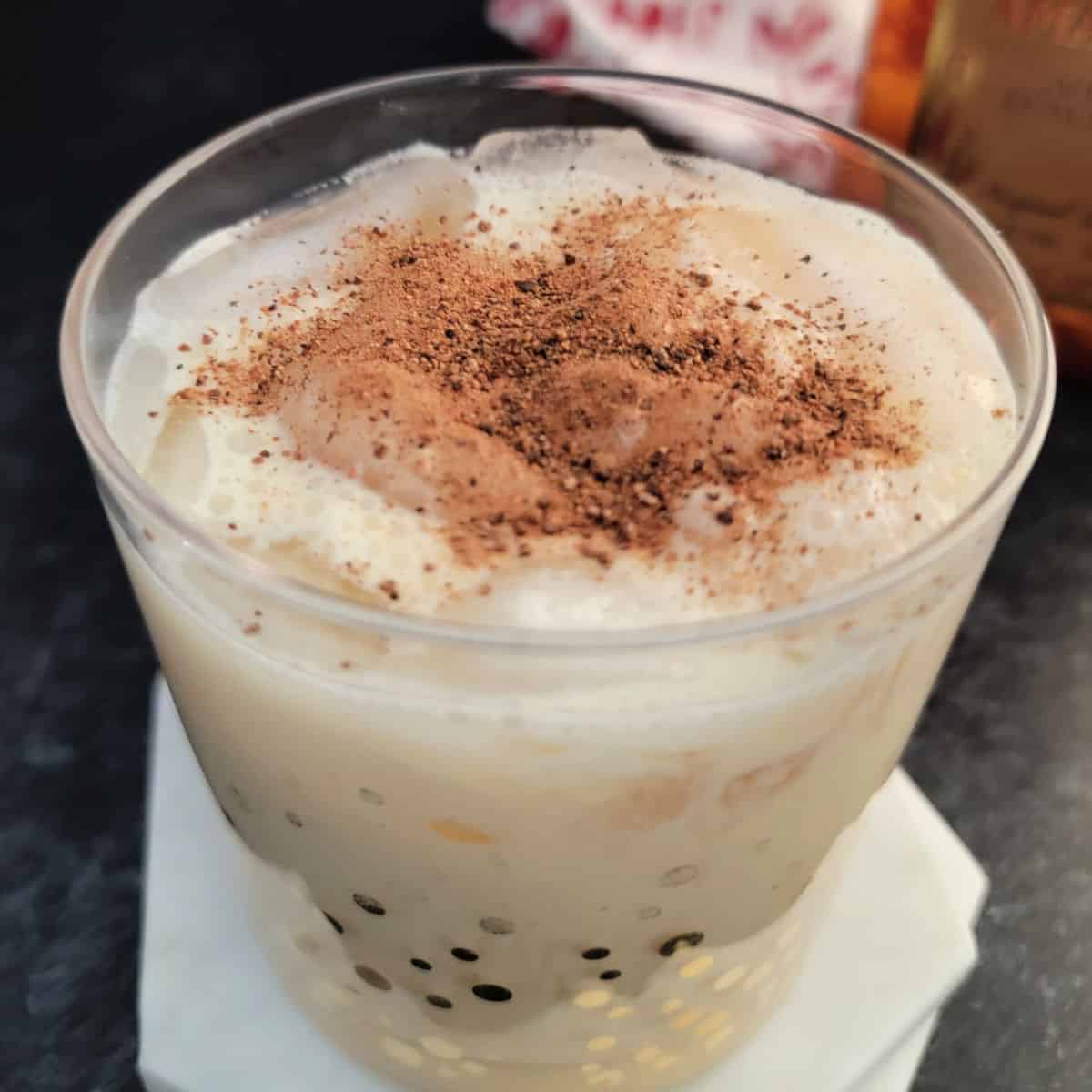 Amaretto Eggnog Cocktail in a gold polka dot glass on a white coaster