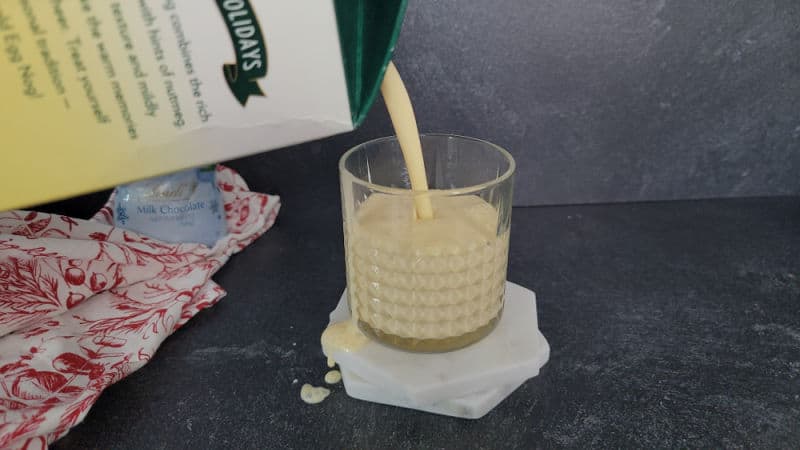 Eggnog pouring into a crystal glass for a bourbon eggnog cocktail