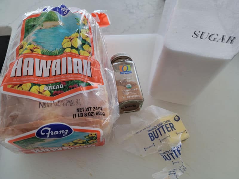 Hawaiian bread, ground cinnamon, sugar, and butter on a counter top