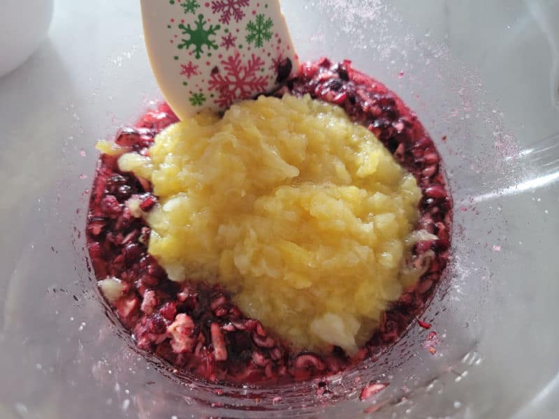 crushed pineapple mixing into shredded cranberries for cranberry dessert salad