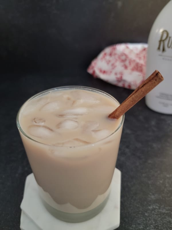 RumChata Iced Coffee in a clear glass with a bottle of RumChata