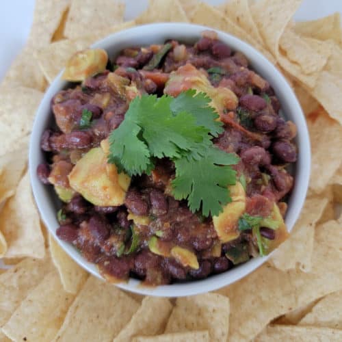 Black bean salsa in a white bowl surrounded by tortilla chips