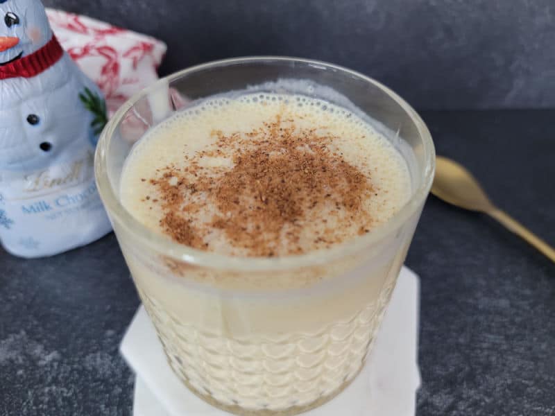 Bourbon eggnog drink garnished with ground nutmeg in a crystal glass