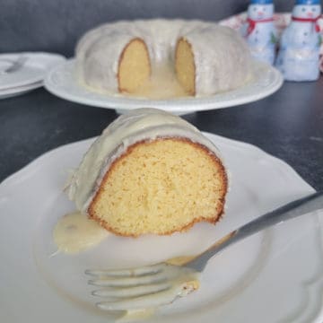 Easy Eggnog Cake with Eggnog Glaze on a white plate with a fork covered in white glaze