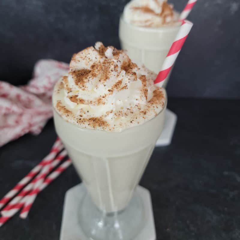 Easy Eggnog Shake in a milkshake glass garnished with whipped cream and nutmeg,