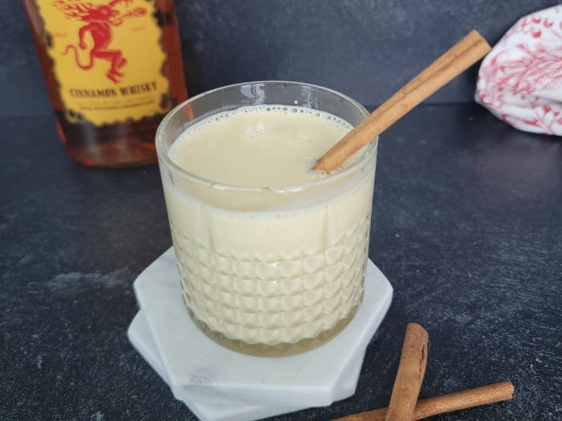 Fireball behind a glass of eggnog with a cinnamon stick in it. 