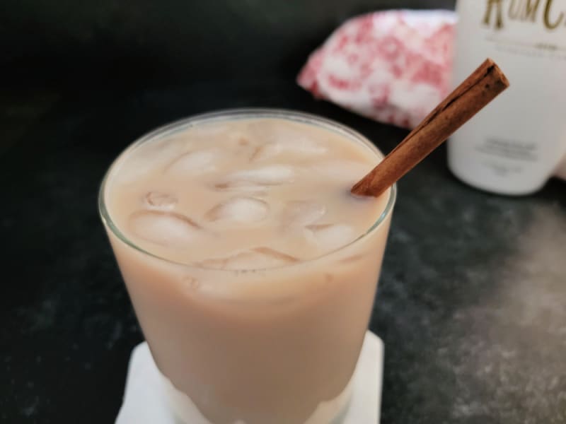 Iced Coffee RumChata in a clear glass next to a bottle of RumChata