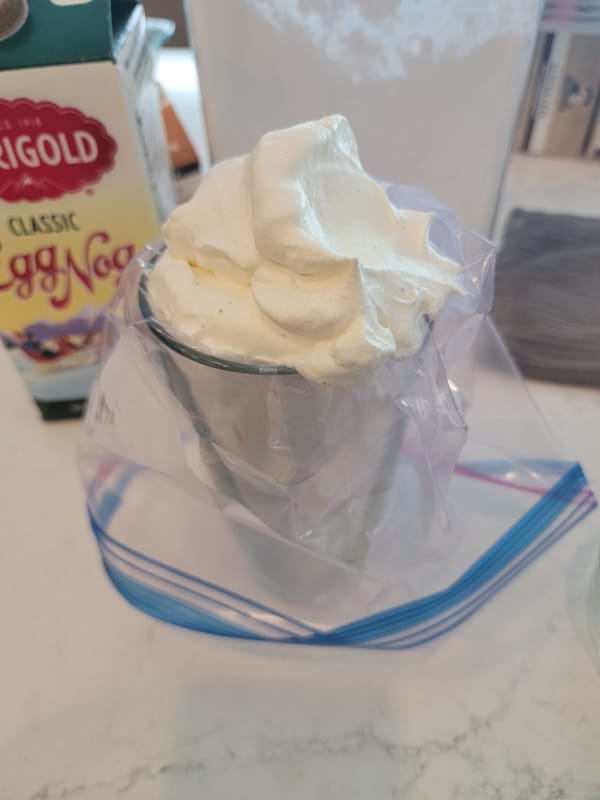 Eggnog whipped cream in a plastic bag in a glass
