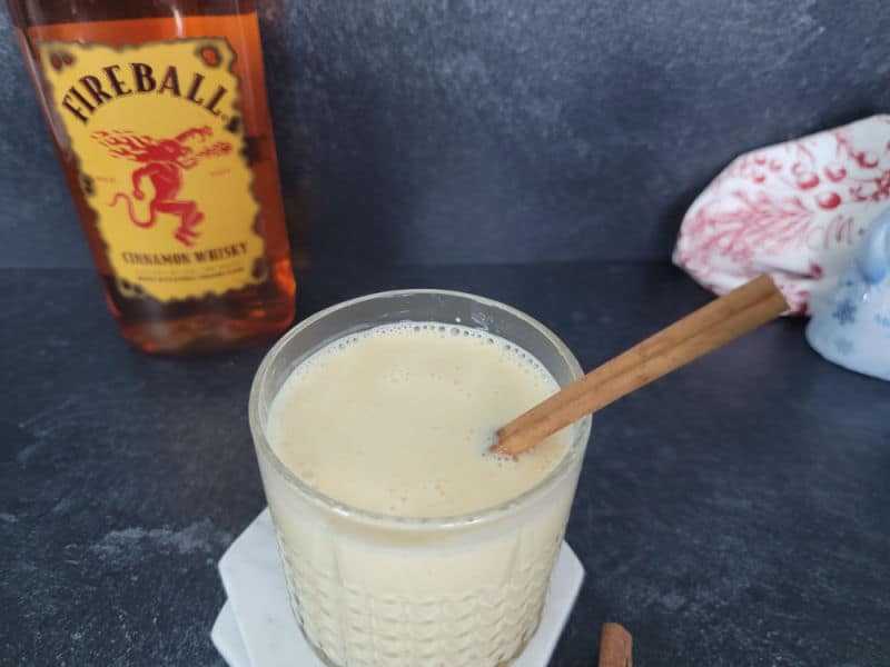 Fireball bottle behind a glass with a cinnamon stick in it. 