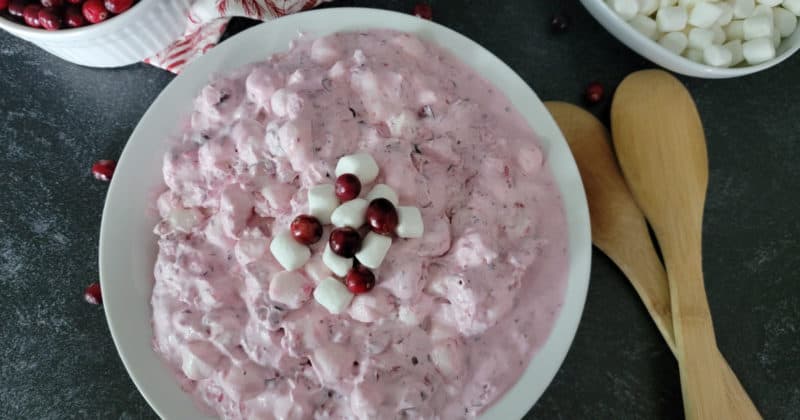cranberry fluff salad in a white bowl with wooden spoons