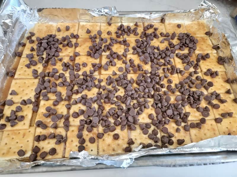 Chocolate chips spread over saltine crackers to make Christmas Crack Saltine Cracker Toffee