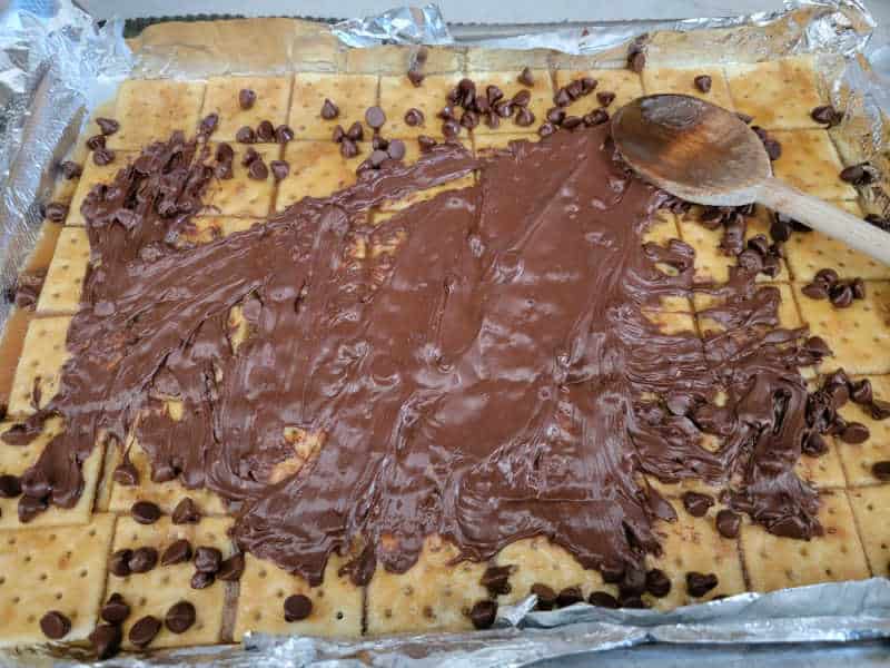 Chocolate chips spread out over saltine crackers to make Christmas Crack