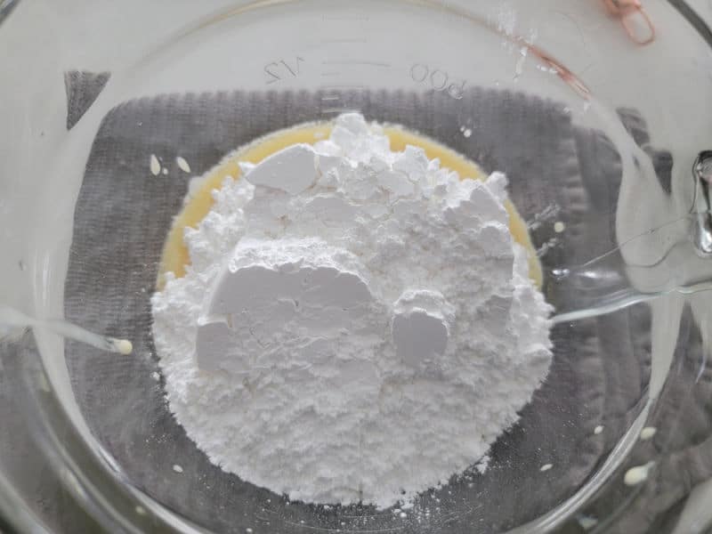 Powdered sugar on top of eggnog glaze in a clear glass bowl 