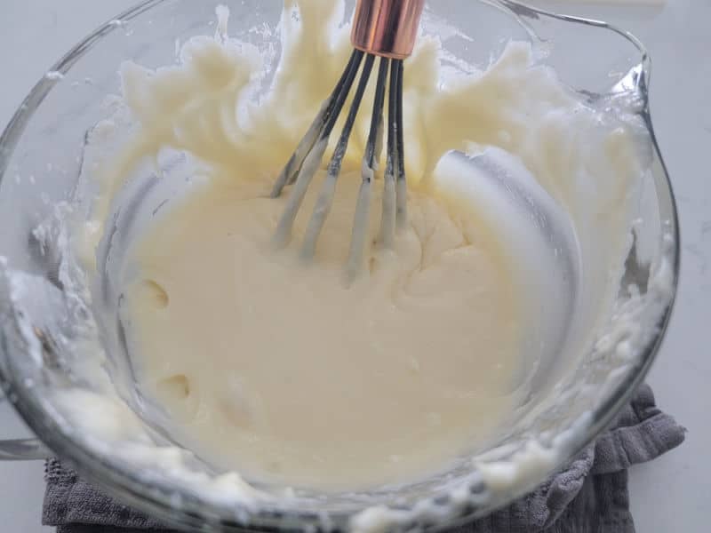 Eggnog glaze being whisked together in a clear glass bowl