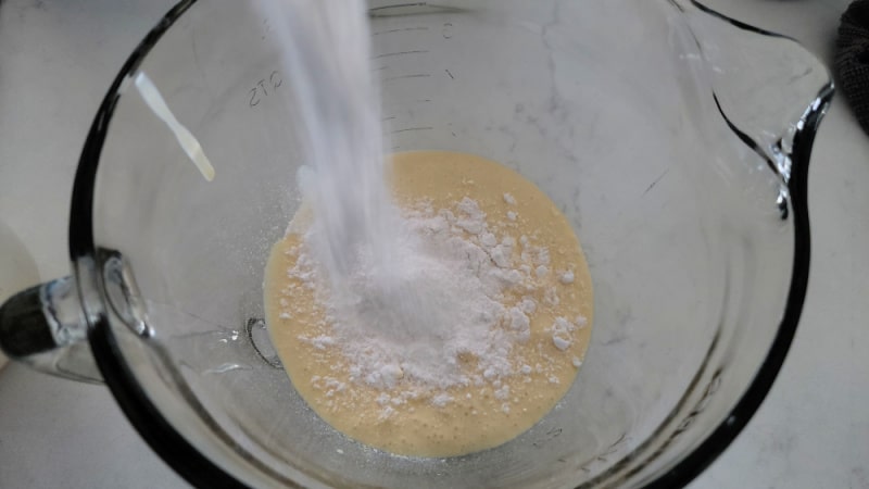 dry vanilla pudding pouring into a glass bowl with eggnog for eggnog pie