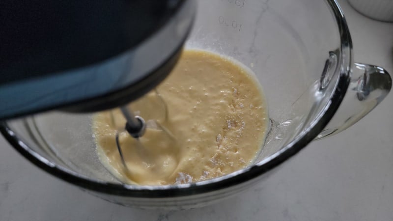 electric hand mixer mixing eggnog pie ingredients in a glass bowl