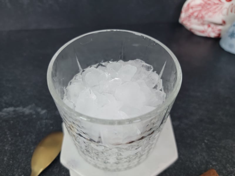 crystal glass with ice in it next to a gold spoon