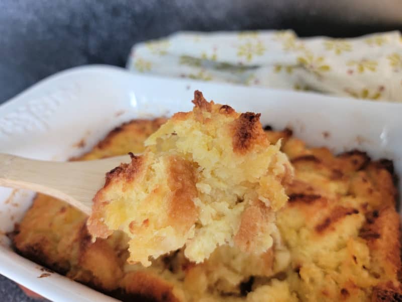 Pineapple stuffing on a wooden spoon above the baking dish