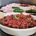 cranberry salsa in a white bowl with jalapenos and cranberries in the background