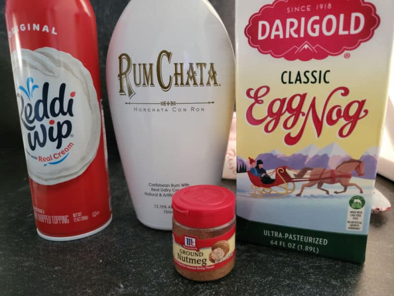 Whipped cream, RumChata, Eggnog, and Ground Cinnamon containers on a counter. 