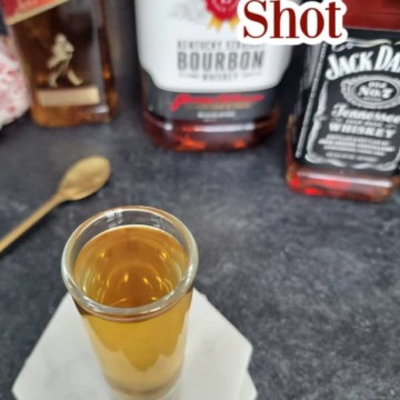 Three wise men shot on a coaster with johnnie walker, jim beam, and jack daniels bottles behind it