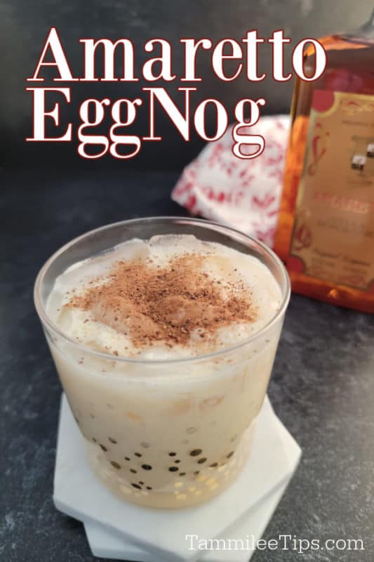 Amaretto Eggnog text printed over a glass with amaretto eggnog garnished in ground nutmeg with a bottle of amaretto