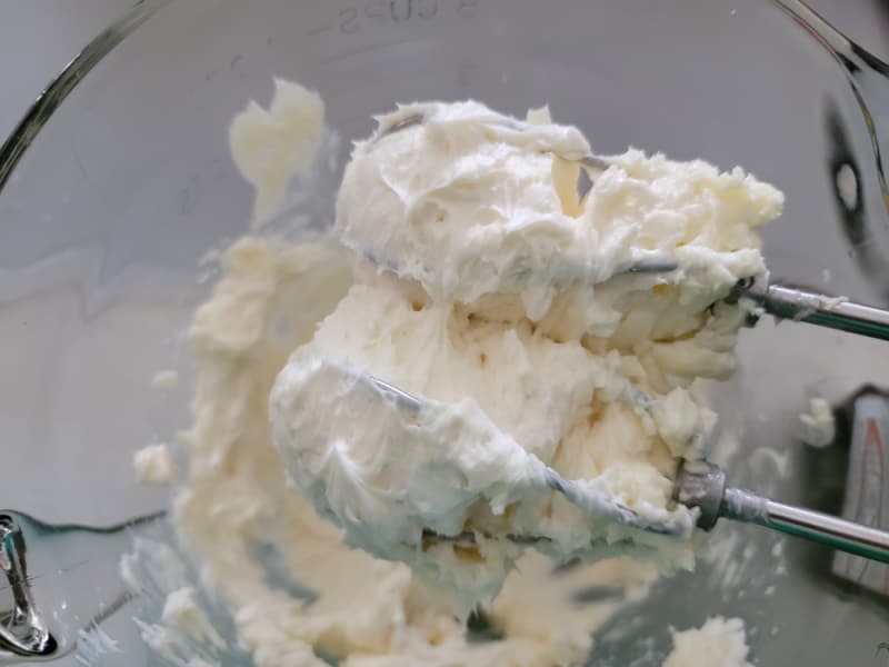 creamed cream cheese on hand mixer beaters in a glass bowl for chocolate chip cream cheese ball