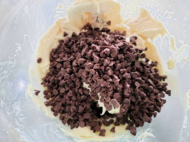 mini chocolate chips on top of cream cheese in a glass bowl for chocolate chip cheese ball