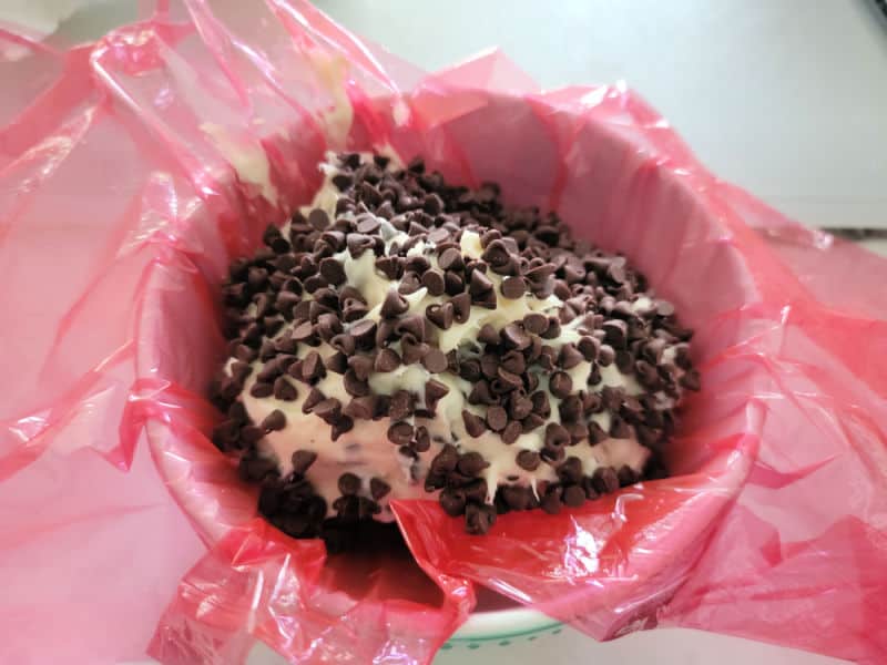 chocolate chip cheese ball in a bowl with red saran wrap