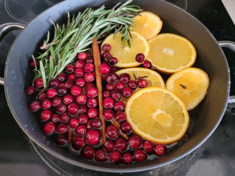 Rosemary, Cranberries, cinnamon stick, and orange wheels in a pot on the stovetop for Christmas Potpourri
