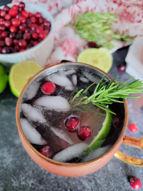 Cranberry Moscow Mule in a copper mug garnished with cranberries and rosemary