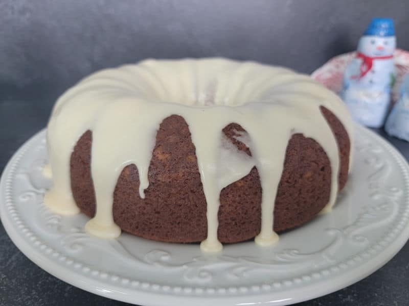 Eggnog glaze dripping over a eggnog bundt cake on a white plate