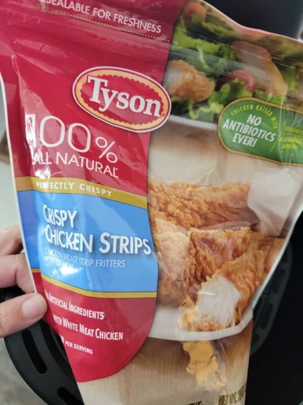 Tyson Crispy Chicken Strips bag held over an air fryer