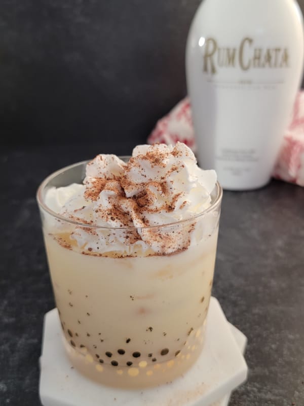 Rumchata bottle behind an eggnog drink. 