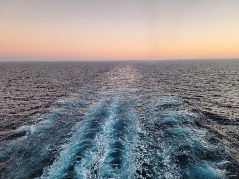 Waves off the back of a cruise ship with the sunset in the background