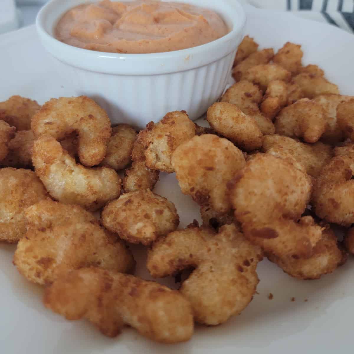 air fried shrimp on a white plate next to a bowl of sauce