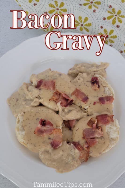 Bacon gravy over biscuits on a white plate with a cloth napkin in the background