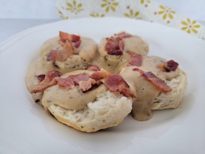 bacon gravy and biscuits on a white plate
