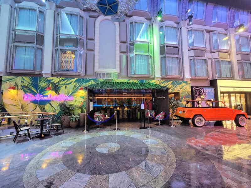 Tropical bar entrance with palm fronds on the wall and a historic open top Jeep