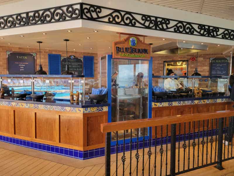 Blue Iguana cantina sign next to counters with servers and servng dishes. 