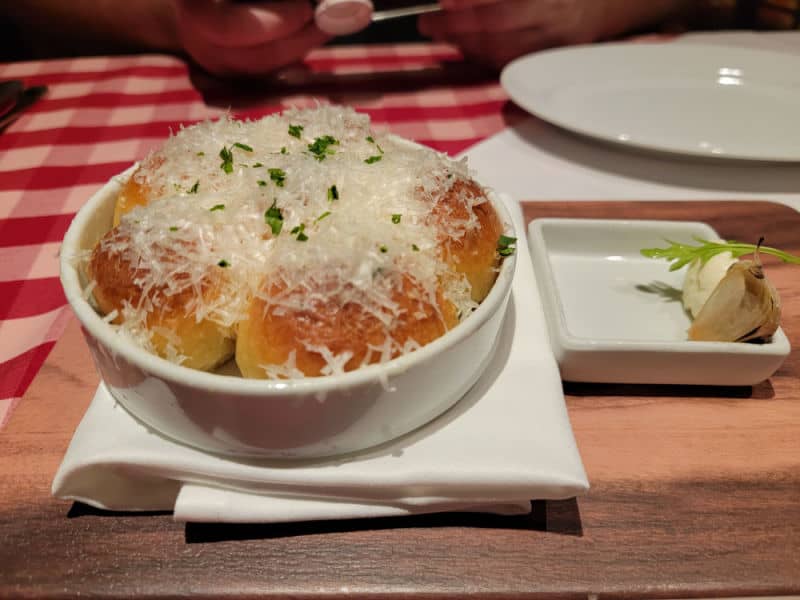 Bread in a white bowl covered in parmesan cheese