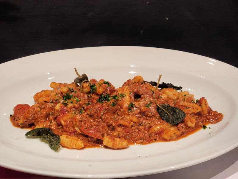 cavatelli pasta on a white plate with basil leaves