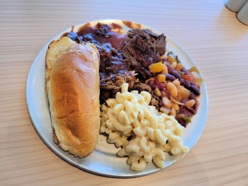 brisket, beans, mac and cheese, and a roll on a white plate