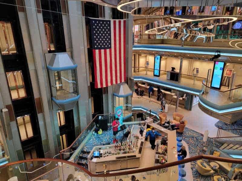 American flag hanging in a cruise ship atrium with multiple levels and the lobby bar